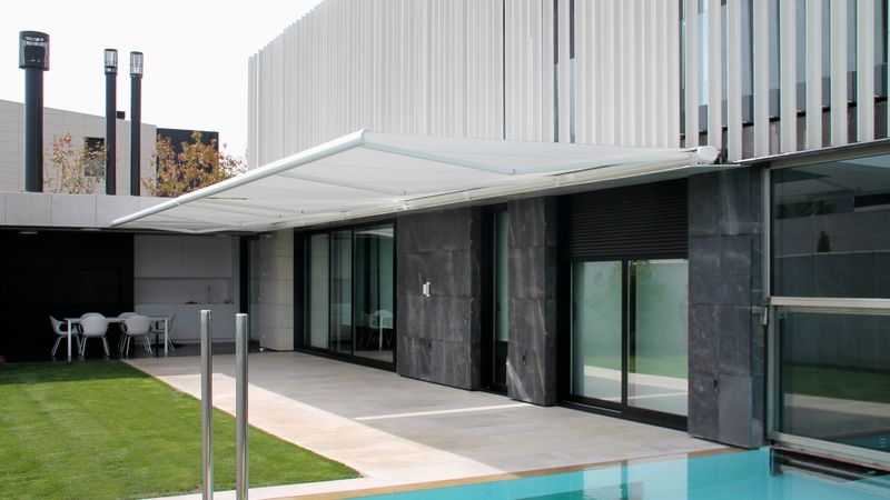Reference image of the markilux 5010 cassette awning on a modern house with a pool in the foreground.