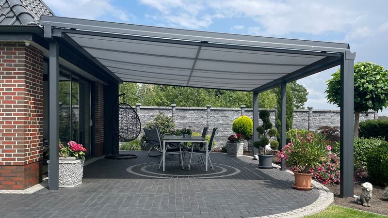 O teto do pátio de uma casa de tijolo está equipado com o toldo de vidro markilux 779.