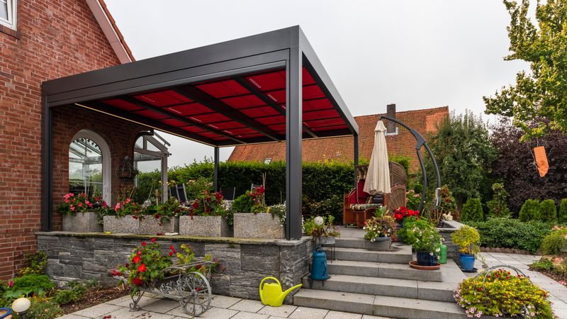 Referentie van een vrijstaande terrasoverkapping markilux markant met rood zonweringdoek.