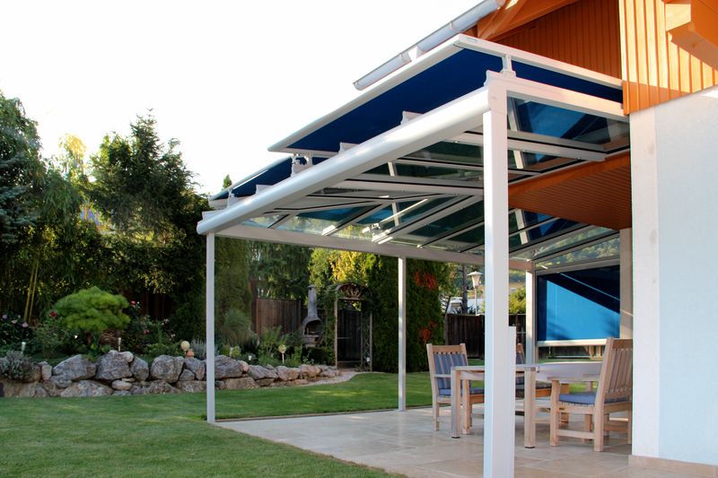 Imagem de referência de um toldo de telhado markilux 870 com estrutura cinzenta e cobertura em tecido azul num telhado de pátio.
