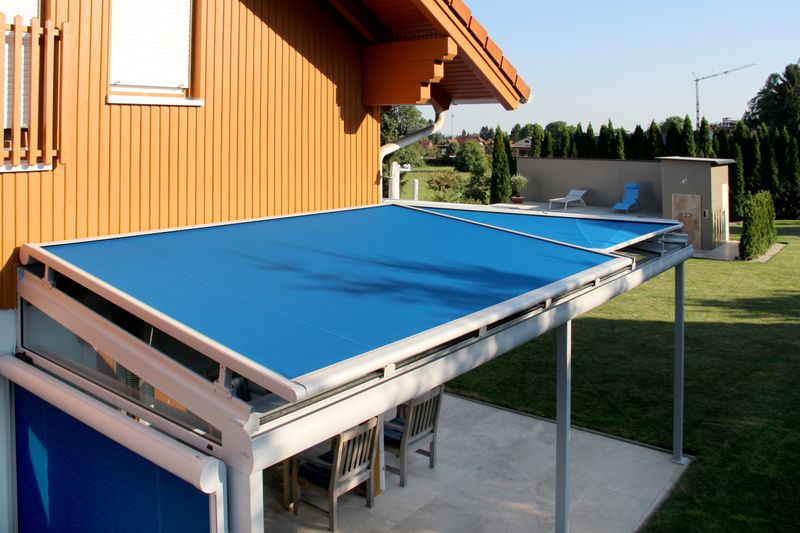 Reference image of a markilux 870 rooftop awning with gray frame and blue fabric cover on a patio roof.