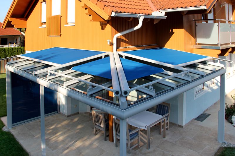 Cubierta de terraza equipada con toldos markilux, lona de tejido azul, entreabierta.