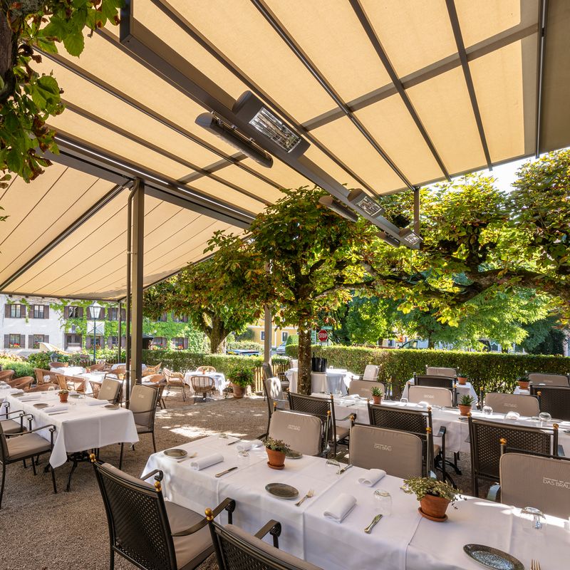 Restaurant terrace covered with a markilux awning system with light fabric cover.