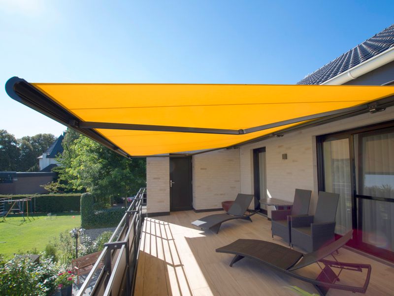 Referentiebeeld: cassettescherm markilux 5010 (grijs schermframe, gele doek) overdekt een balkon.
