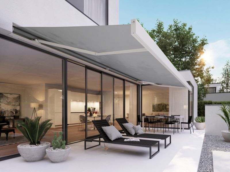 Tenda da sole a cassonetto markilux 3300 bianca con telo della tenda da sole grigio su una casa bianca con terrazza elegante.