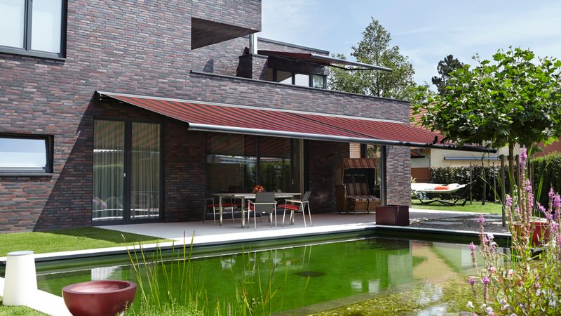 Referensbild: Kassettmarkis markilux 6000 på ett hus med mörka klinkerplattor.