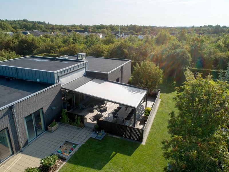 Vista dall'alto di un giardino moderno con terrazza coperta da una pergola stretch di markilux.