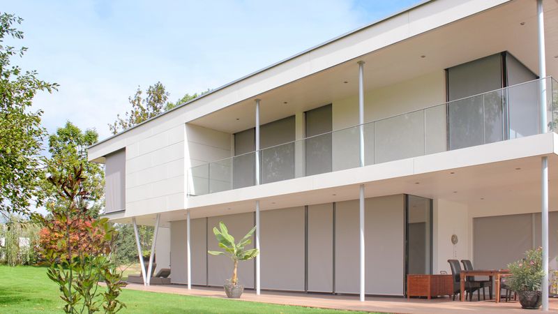 Les fenêtres d'une maison à toit plat sont ombragées par des stores de fenêtre markilux 620 gris.