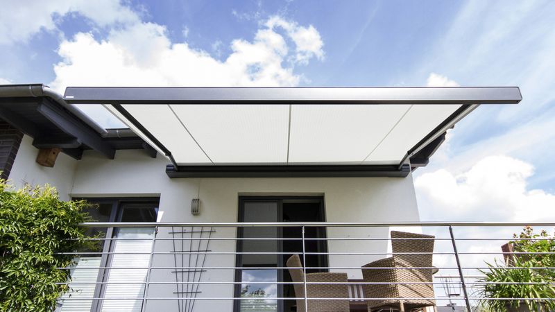 Kassettenmarkise markilux 970 mit hellem Tuch an Balkon eines weißen Hauses