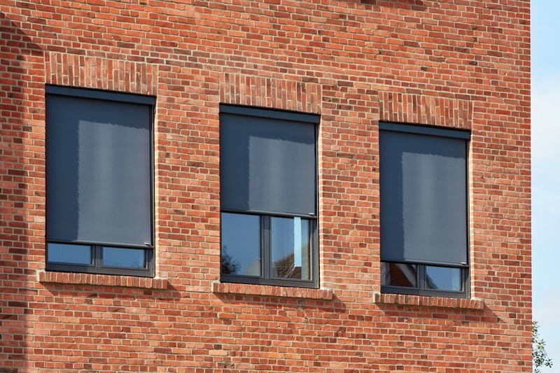 Referenzobjekt: Backsteingebäude mit Fenstermarkisen markilux 620 mit grauem Tuch.