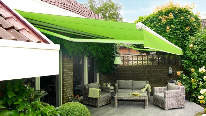 White awning markilux 1710 with bright green fabric cover and valance over a terrace in a building niche, gloss chrome elements in the side caps.