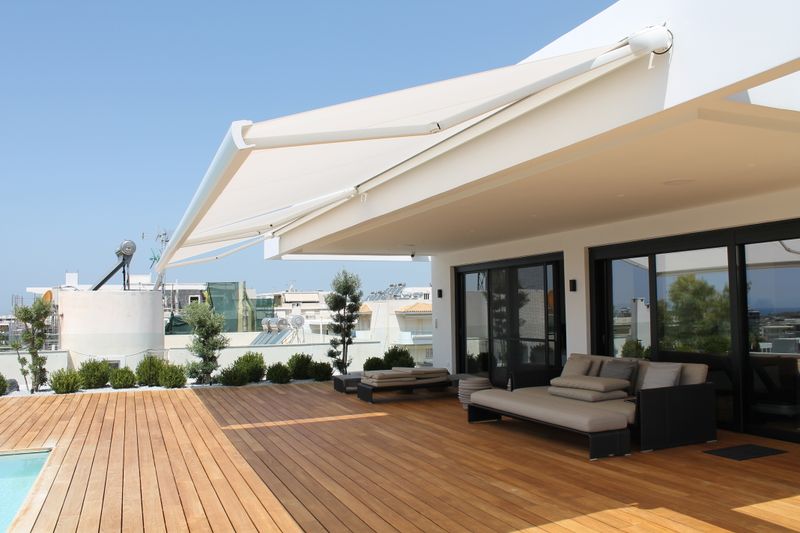 Tenda da sole a cassonetto bianca MX-3 su una terrazza in legno a bordo piscina in Grecia.
