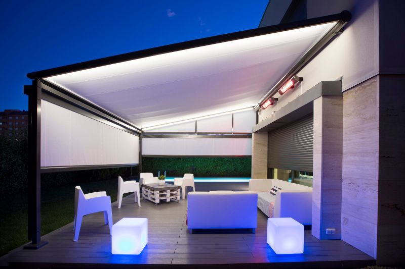 Combinazione di markilux pergola e tenda verticale con teli in tessuto bianco. Dotata di illuminazione a LED e radiatore termico. Ripresa serale.