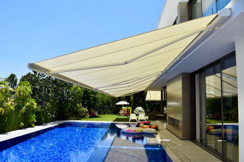 Reference picture of cassette awning markilux 5010 (white) on a modern house with pool in the sun.