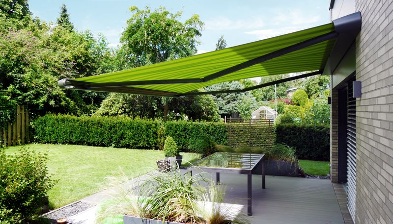 reference image: awning mx-1 compact in gray with green striped fabric cover on a single-family house.
